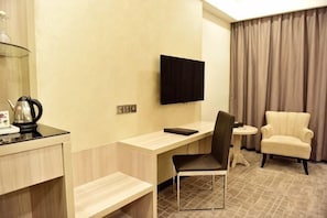 Una habitación de hotel con escritorio, silla, televisor y dos sillones.