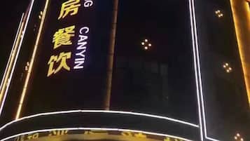 A building with illuminated signage in yellow characters, indicating a hotel or similar establishment.