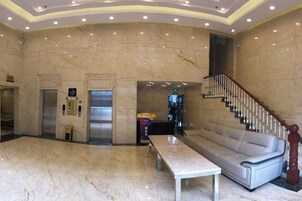 Un vestíbulo con suelo de mármol, un sofá, una mesa, un ascensor y una escalera.