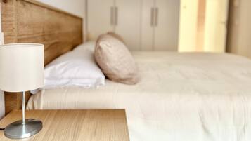 Un lit bien fait, avec une tête de lit en bois, une lampe de chevet et une table de chevet.