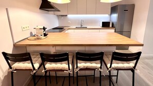 Uma cozinha moderna com uma ilha central, quatro cadeiras, micro-ondas e geladeira.