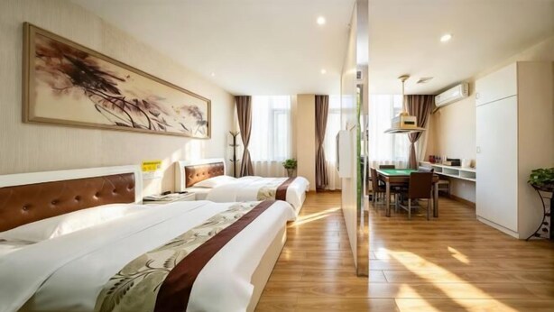 Una camera d'albergo con due letti, un'area pranzo e angolo cottura.