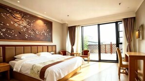 Una camera d'albergo con un grande letto, una scrivania, una sedia e un balcone con vista.