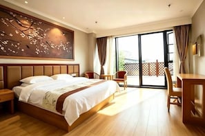 Habitación de hotel con una cama grande, un escritorio, una silla y un balcón con vistas.