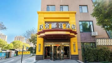 A hotel entrance with a yellow facade and black signage.