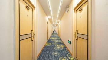 A hotel hallway with carpeted floors, wooden doors, and a long corridor.
