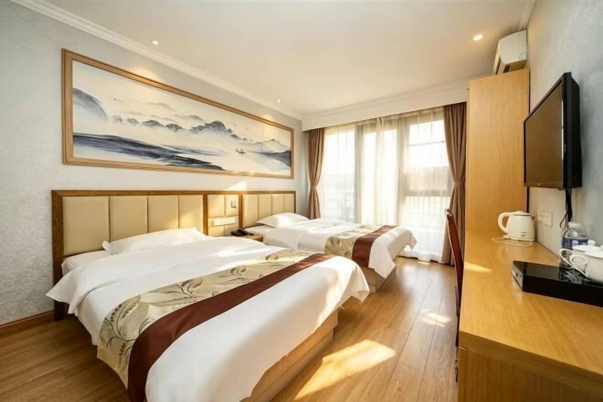 Habitación de hotel con dos camas, un cuadro en la pared, televisión y cafetera.