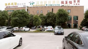 A parking lot with several cars, a building with signage, and trees in the background.