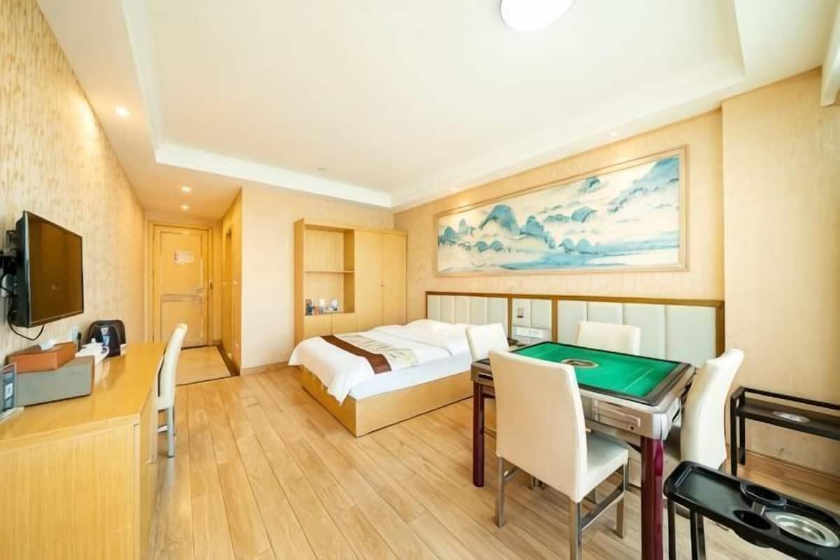 Una habitación de hotel con cama, escritorio, mesa de billar y un cuadro en la pared.