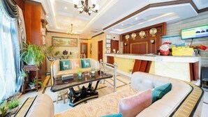Una hall d'albergo con un divano, un tavolino da caffè, un lampadario e la reception.