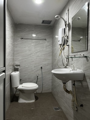 A compact bathroom with a toilet, sink, and shower. - Homestay55 (Masai)