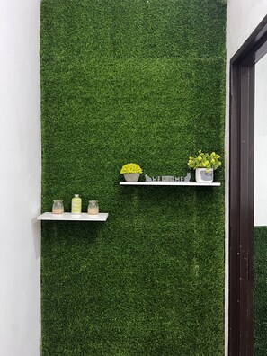 Pared con césped artificial, dos estantes con adornos y un marco de puerta.