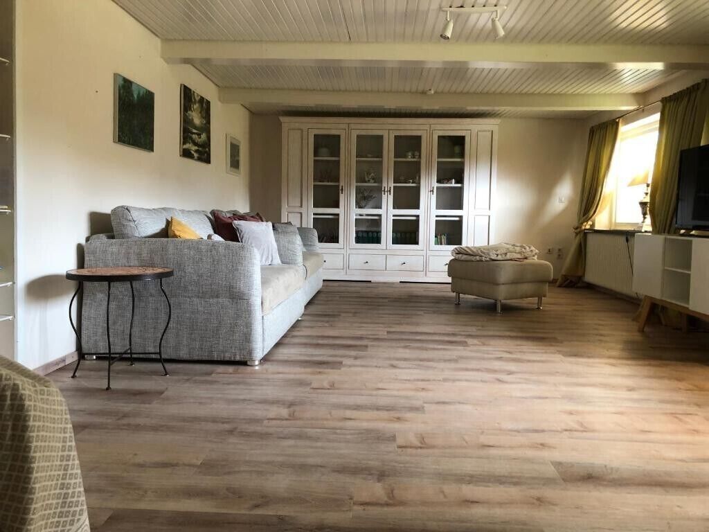 Ein Wohnzimmer mit einer Couch, einem kleinen Tisch, einem Schrank und einem Fernseher.