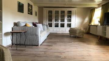 Ein Wohnzimmer mit einer Couch, einem kleinen Tisch, einem Schrank und einem Fernseher.