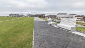 A park with a paved walkway, benches, and a grassy field.