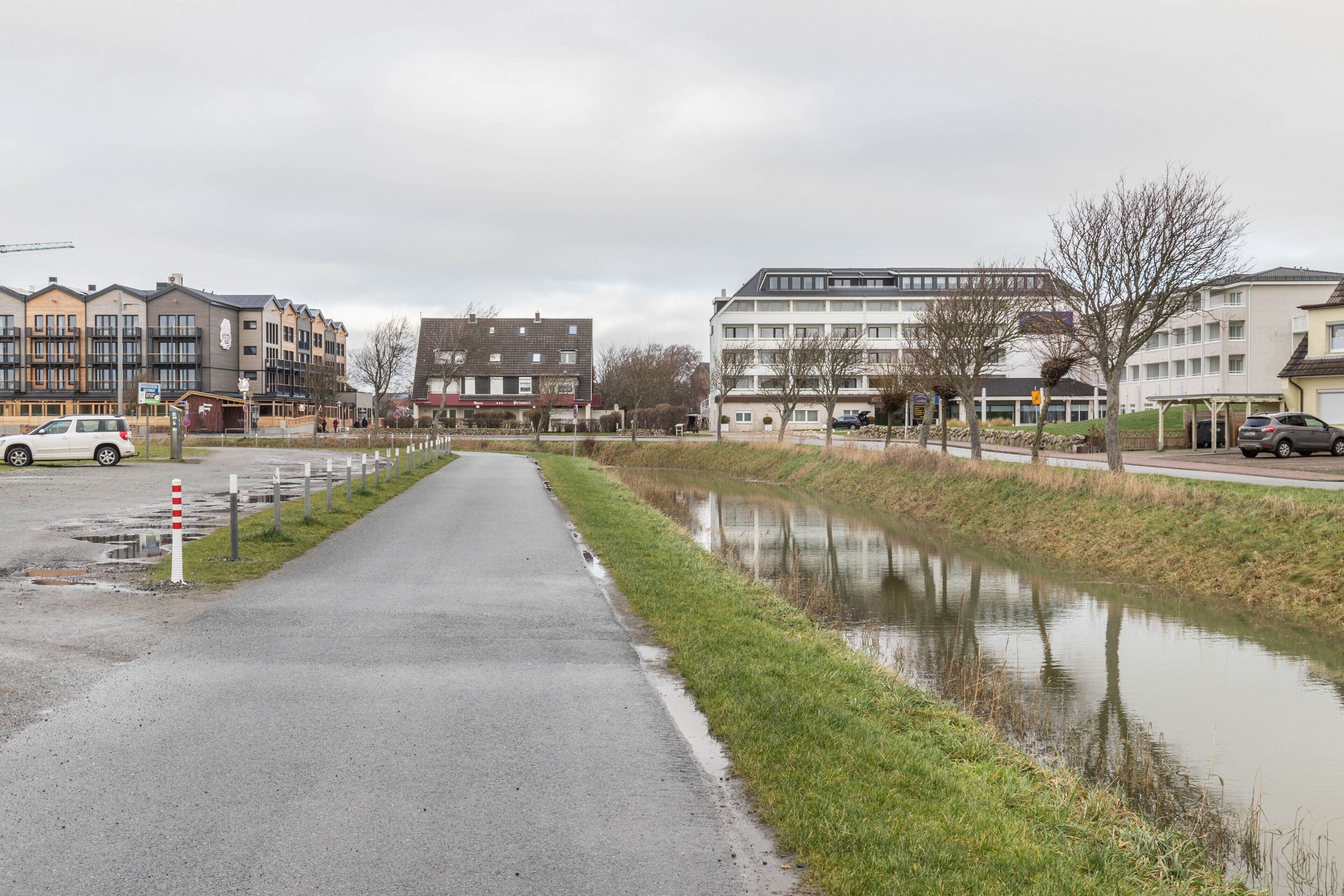 A residential area with multi-story buildings, a paved road, and a canal.