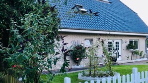 A house with a blue roof, a white picket fence, and a garden.