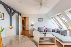 Un salon moderne comprenant un canapé, une table basse, une table à manger et un ventilateur de plafond.