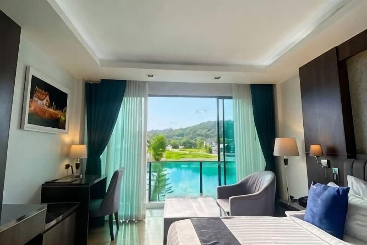 Habitación de hotel con cama, escritorio, silla y vista a un cuerpo de agua.