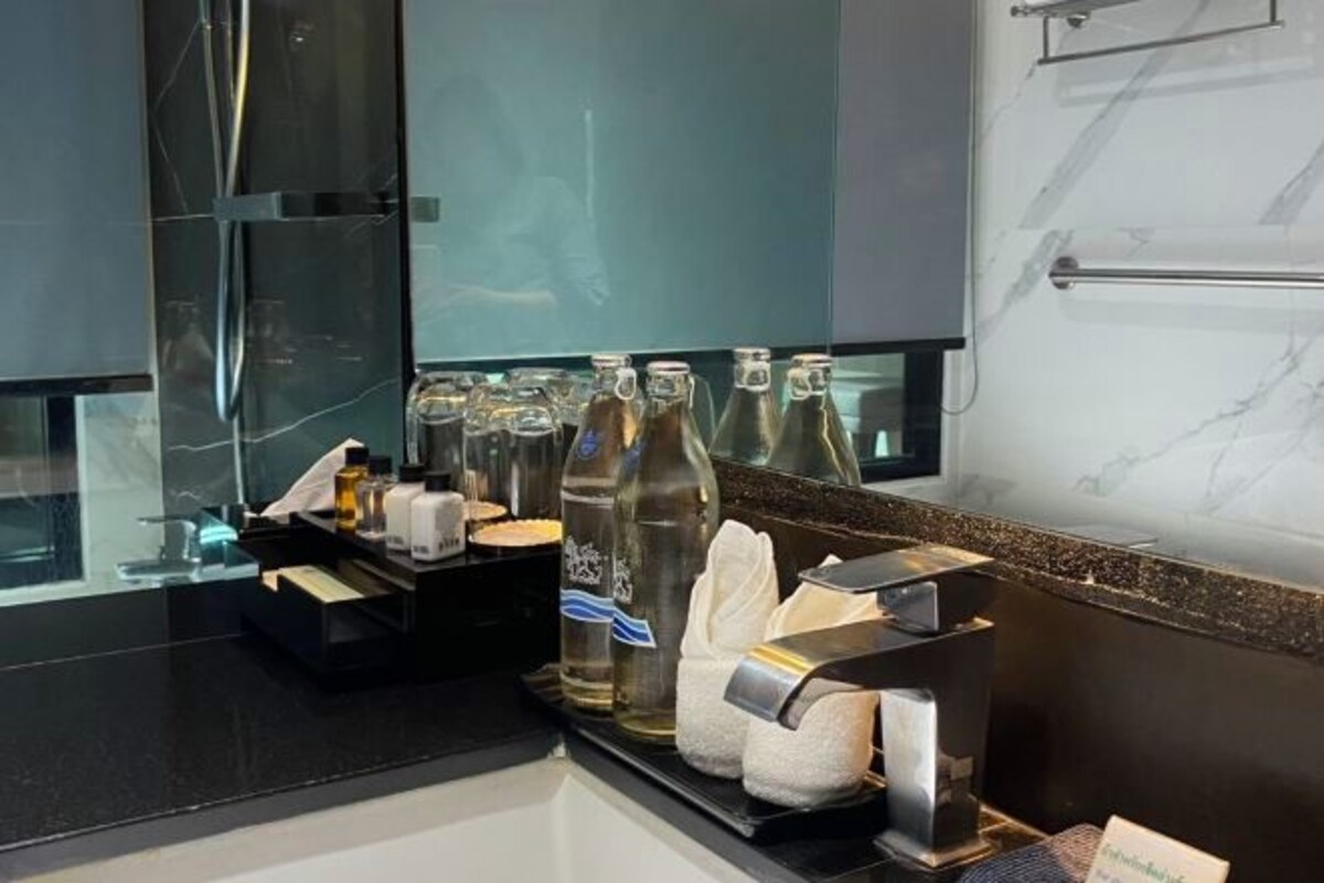 Un baño moderno con cabina de ducha de vidrio, encimera negra y pared de mármol.