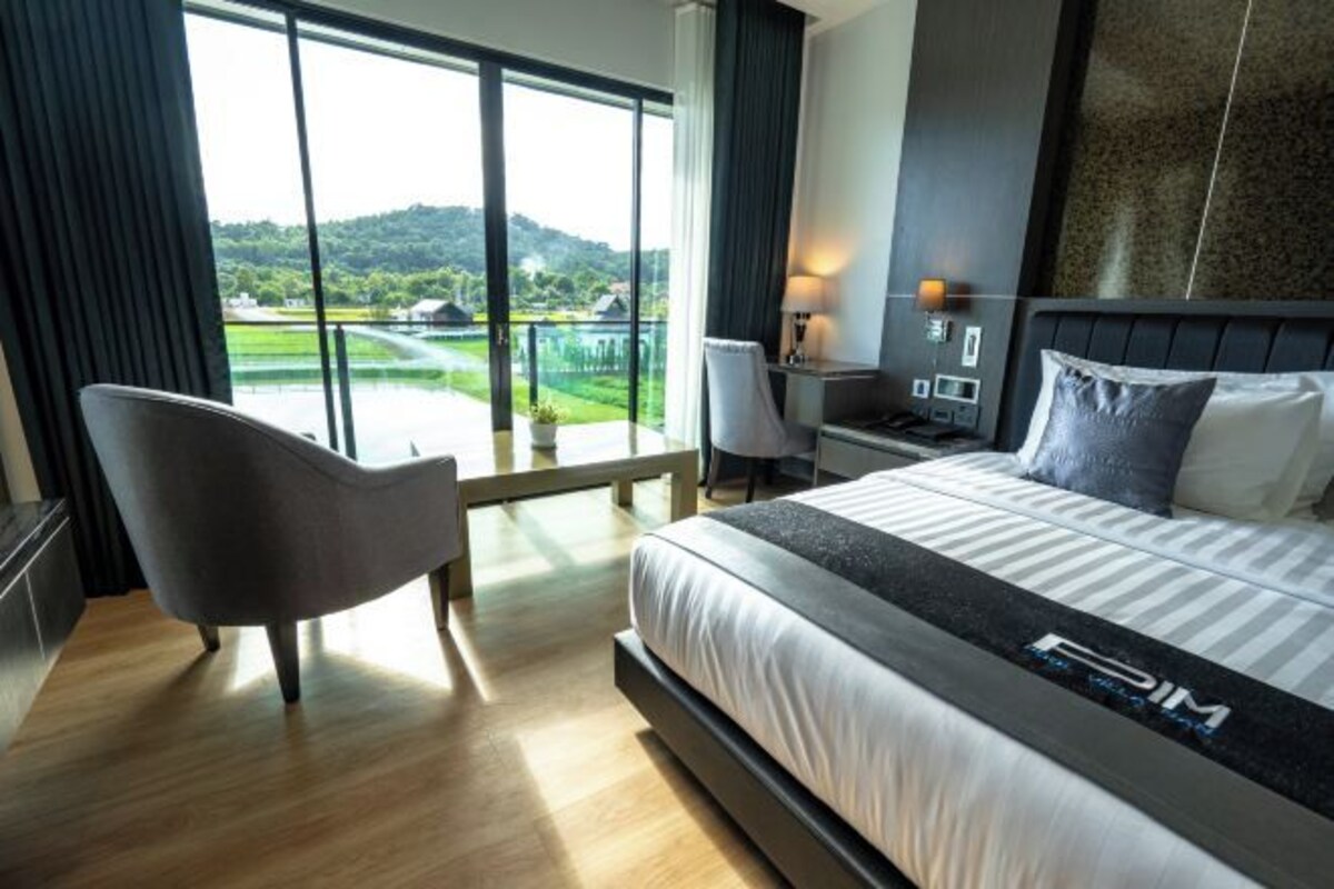 Habitación de hotel con una cama grande, una silla, un escritorio y vistas a un campo de golf.