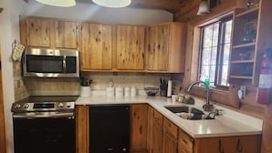 A kitchen with wooden cabinets, stainless steel appliances, and a window providing natural light. - Cozy cabin in the woods. 12 min from the Angel Fire ski resort; 6 to golf course (Angel Fire)