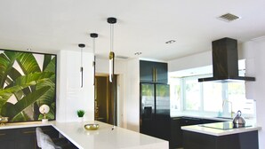 Een moderne keuken met een centraal eiland, zwarte kastjes en hangende lampen.