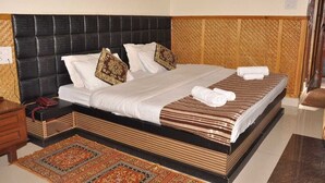 Un lit bien fait, avec une couvre-lit à rayures, une tête de lit noire et des coussins décoratifs.