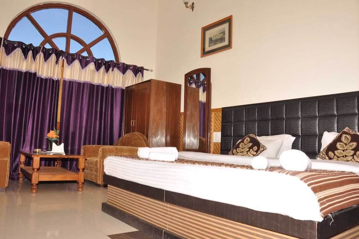 A hotel room with a large bed, a wooden headboard, a wooden side table, and a sofa.