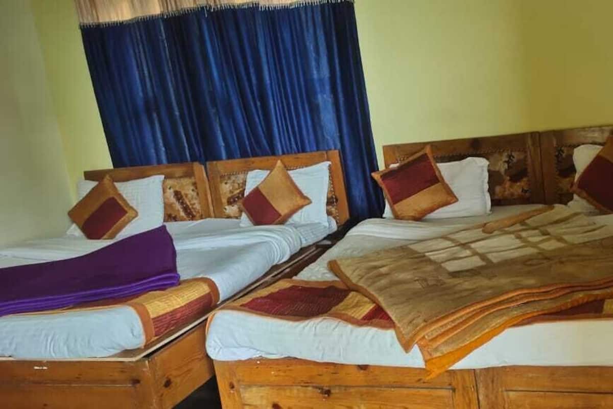 A double bed with a wooden headboard and two single beds with wooden headboards.