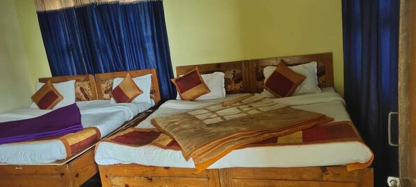 Una cama doble con cabecera de madera y dos camas individuales con cabeceras de madera.