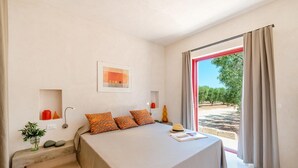A modern bedroom with a bed, bedside tables, a window with curtains, and a view of an outdoor area.