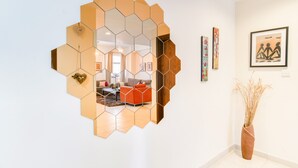 A modern interior with a hexagonal mirror, a red sofa, and a vase with dried plants. - Executive Towers Amazing 1BR Onsite Pool Business bay (Dubai)