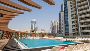 A swimming pool with lounge chairs, surrounded by high-rise buildings. - Executive Towers Amazing 1BR Onsite Pool Business bay (Dubai)