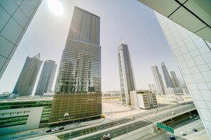 A modern high-rise building with a glass facade, surrounded by other tall buildings and a busy highway. - Executive Towers Amazing 1BR Onsite Pool Business bay (Dubai)