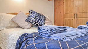 Una cama bien hecha con ropa de cama estampada, un armario de madera y una lámpara sobre la cama.