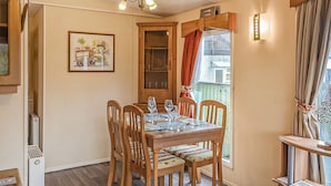 Un comedor con una mesa de madera dispuesta para cuatro personas, rodeado de sillas con asientos acolchados.