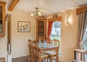 A dining area with a wooden table set for four, surrounded by chairs with cushioned seats.