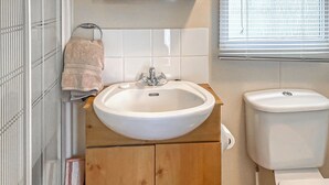 Un baño con lavamanos, inodoro y un mueble de madera.