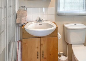 A bathroom with a sink, toilet, and wooden cabinet. - Traditional yet comfortable caravan with one double and one twin. (Dolgellau)