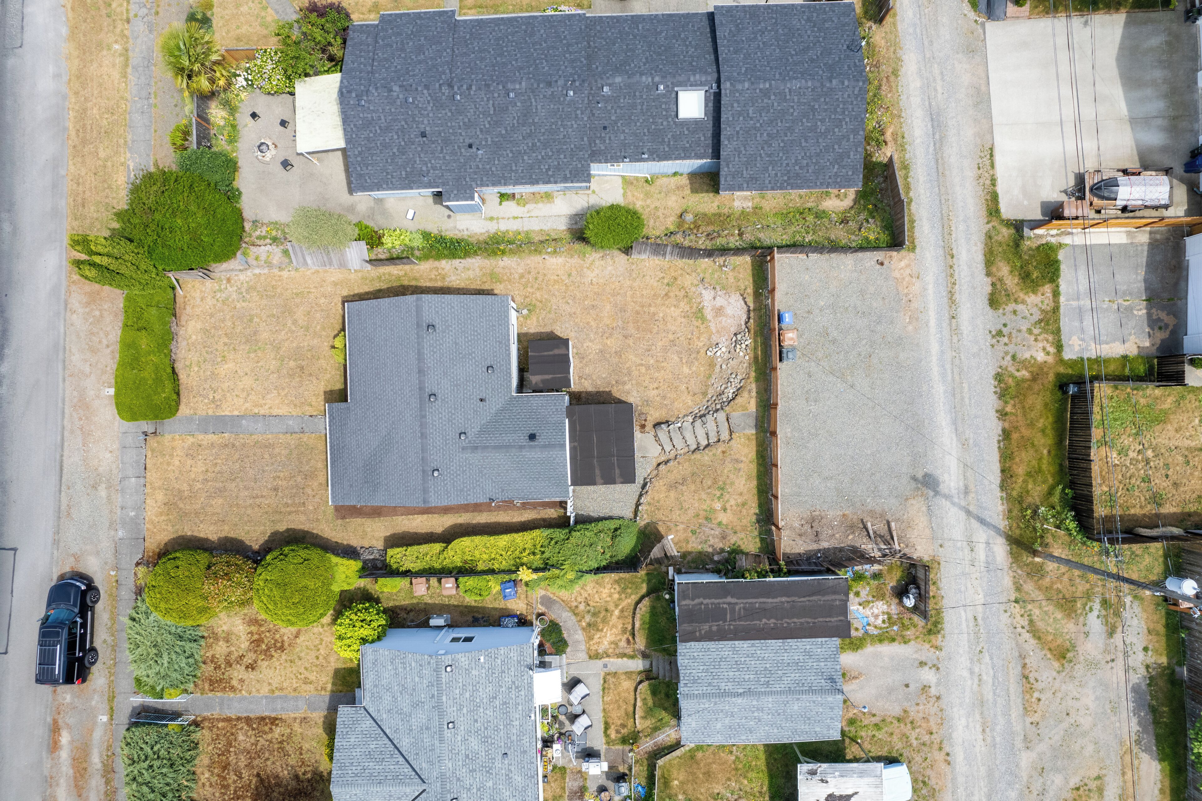 Vue aérienne d’un quartier résidentiel avec plusieurs maisons, une allée et une voiture garée.