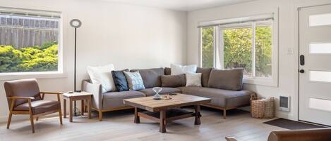 A modern living room with a sofa, armchairs, a coffee table, and a side table.