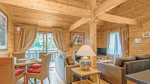L’intérieur d’un chalet en bois comprend un coin repas, un canapé, un téléviseur et une cheminée.