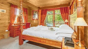 Une chambre dans une cabane en bois, avec un lit à baldaquin, un bureau et une chaise.