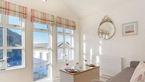 A room with large windows, a dining table with a red wine glass, a mirror, and a radiator.