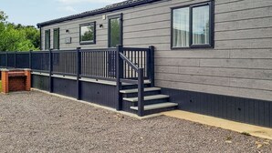 A modern building with a grey exterior, a black railing, and a set of stairs leading to a door. - 1 bedroom accommodation in Woodhall Spa (Woodhall Spa)
