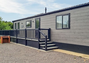 A modern building with a grey exterior, a black railing, and a set of stairs leading to a door.