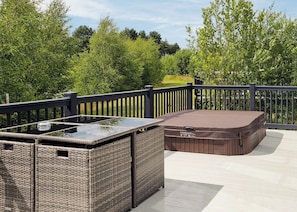 Una terraza con mobiliario de mimbre y un jacuzzi.