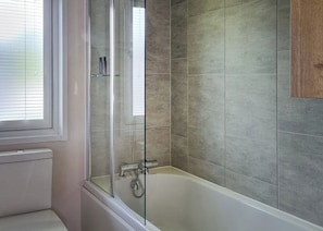 A bathroom with a glass-enclosed shower, a bathtub, and a toilet.