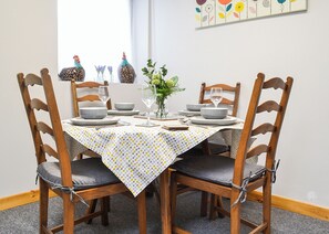 A dining table set with plates, bowls, and glasses, surrounded by wooden chairs with cushioned seats. - 2 bedroom accommodation in Dolgellau (Dolgellau)